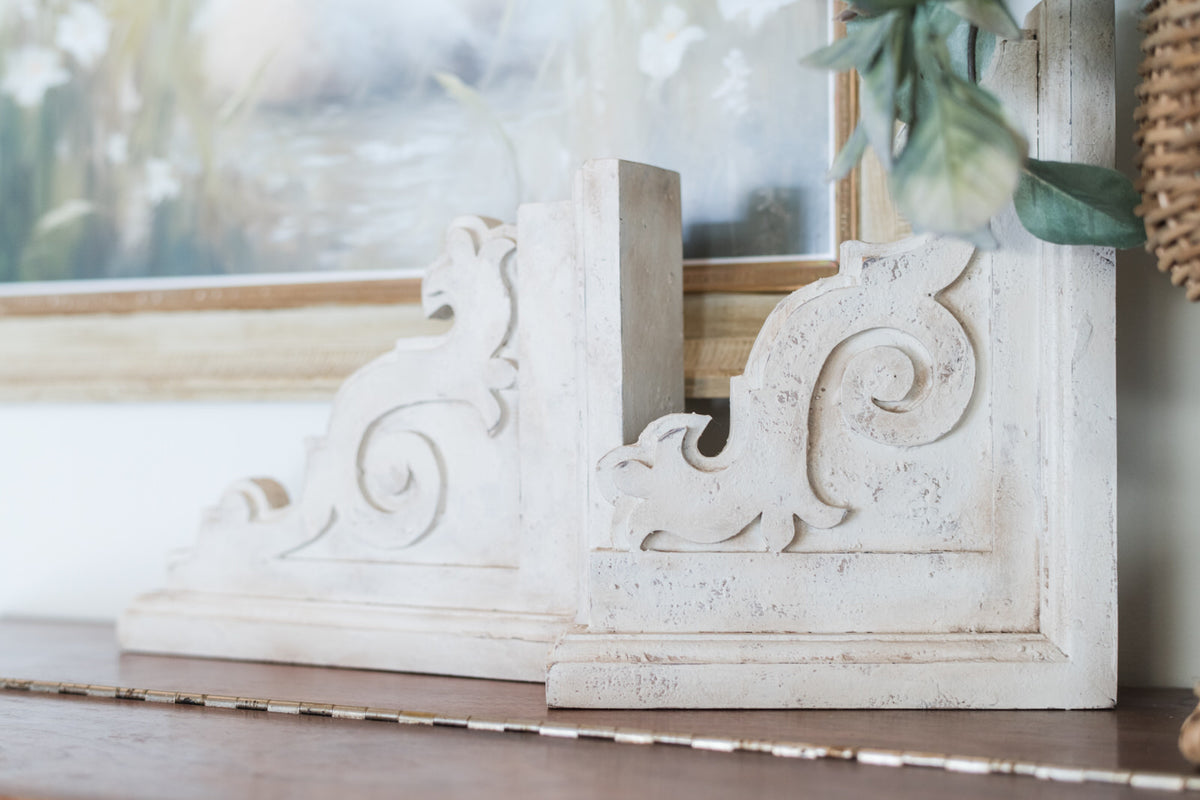 Decorative white corbels with intricate carvings on a wooden surface.