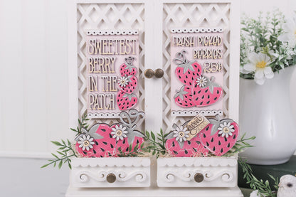 Decorative wooden inserts with pink strawberry designs and text on a white surface.