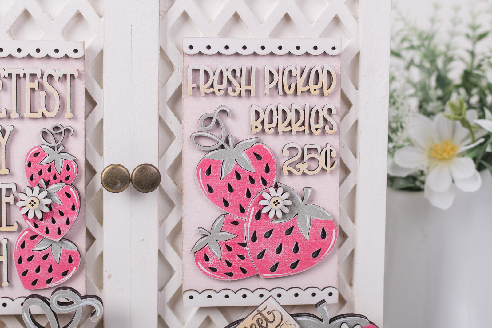 Decorative sign with pink strawberries and text on a white background