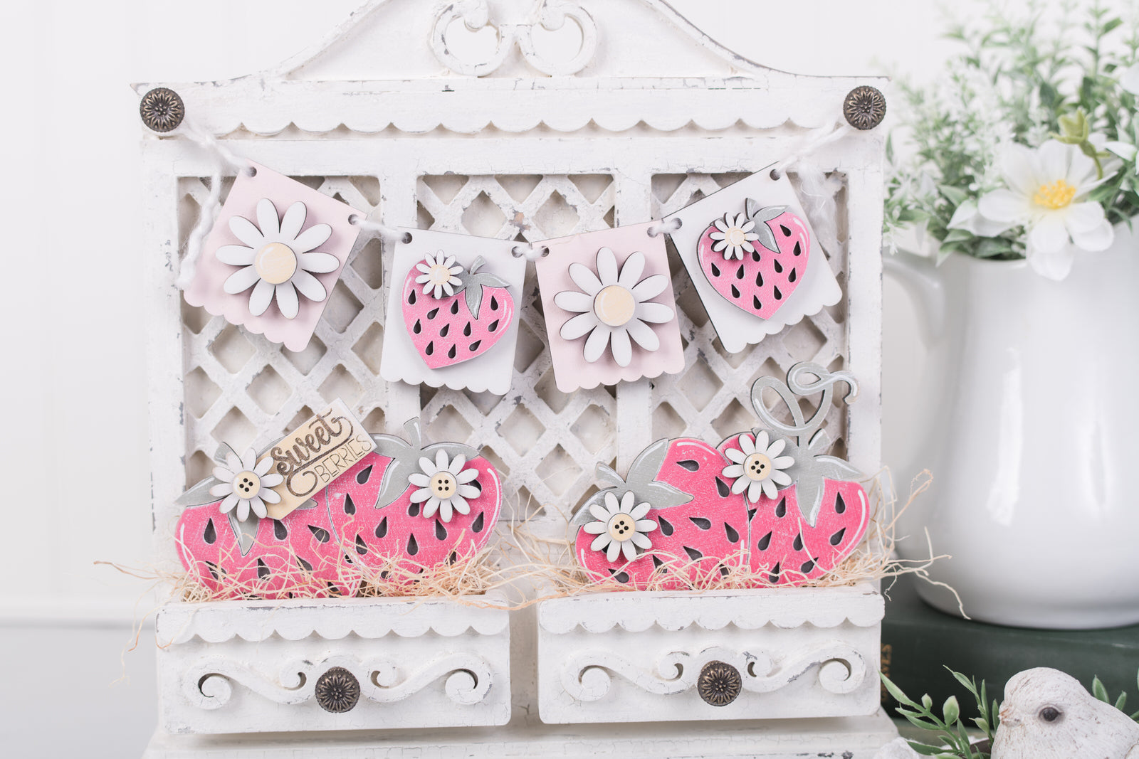 Decorative white cabinet with pink strawberry cutouts on a white background