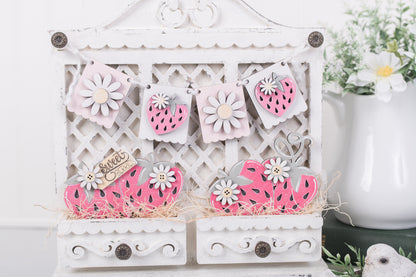Decorative white cabinet with pink strawberry cutouts on a white background