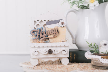 Decorative insert for a cottage drawer with 'Honey' on a white surface with a blurred background