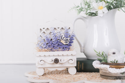 Decorative items including a small white stand with a butterfly ornament, a white pitcher, and a book on a light surface.