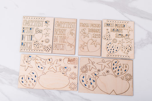 Set of wooden cutouts with strawberry designs on a white surface