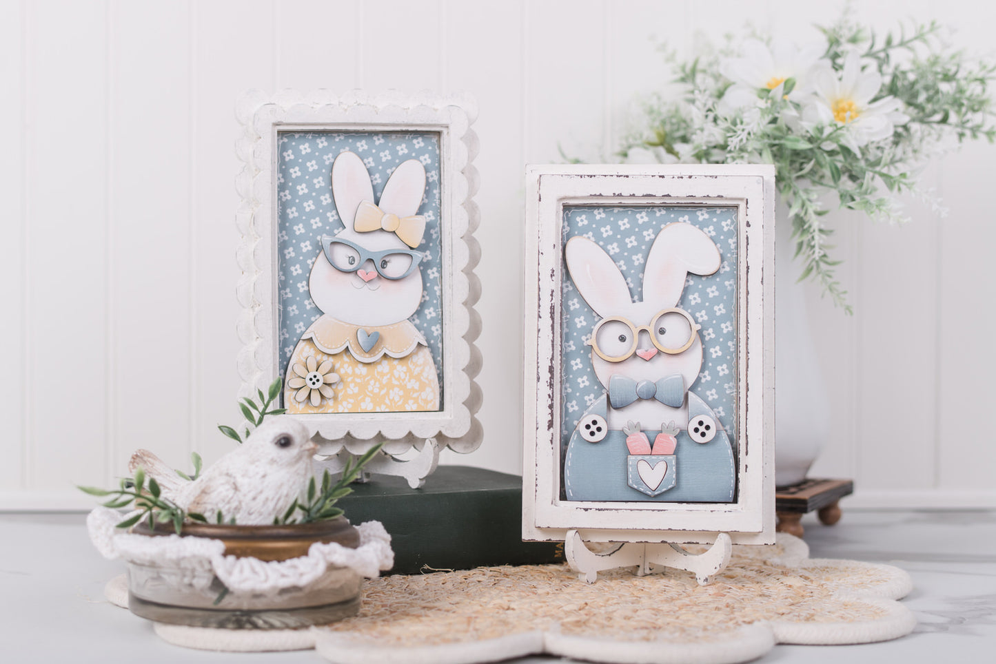 Two framed illustrations of bunnies with decorative elements on a white surface.