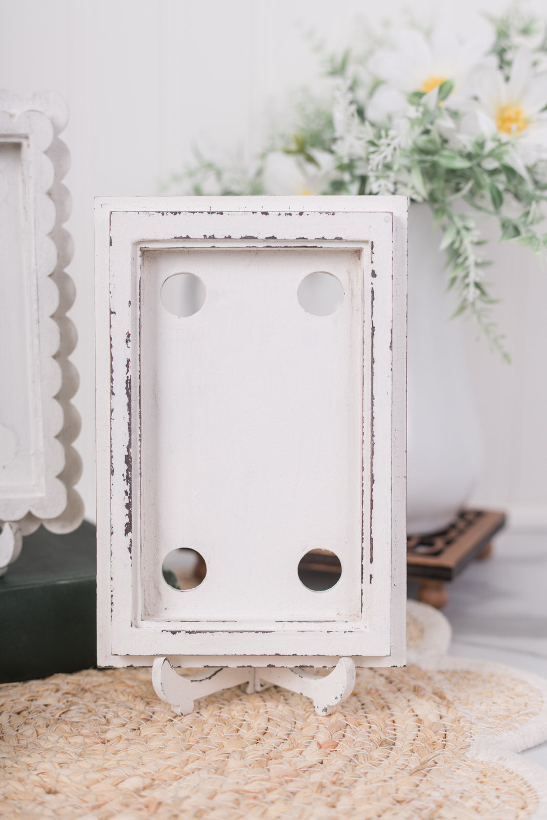 White decorative scallop frame on a textured surface with blurred floral background