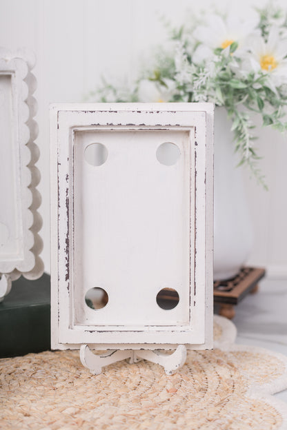 White decorative scallop frame on a textured surface with blurred floral background