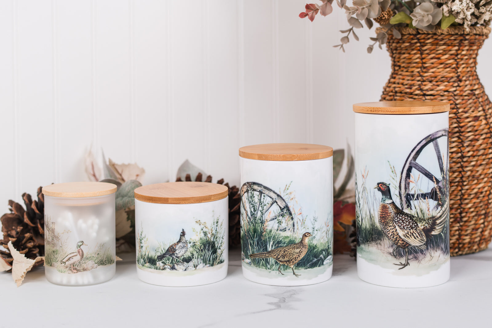 Set of ceramic bathroom canisters with wooden lids featuring game bird designs on a white surface.