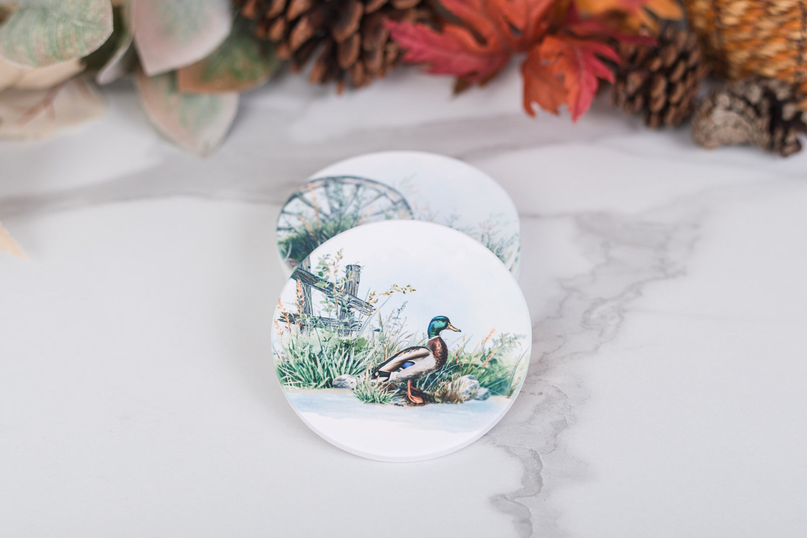 Round coaster with a duck design on a marble surface with decorative elements.