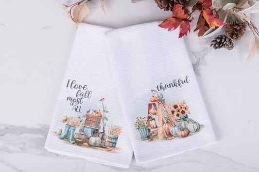 Two white towels with autumn-themed designs and text on a light background.