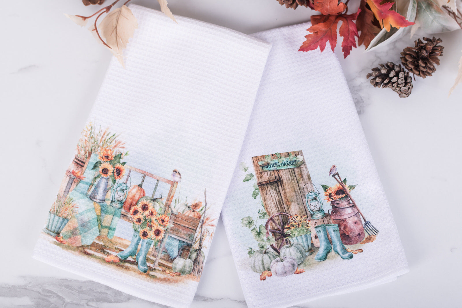 Two decorative towels with autumn-themed designs on a white surface.