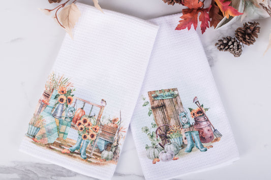 Two decorative towels with autumn-themed designs on a white surface.