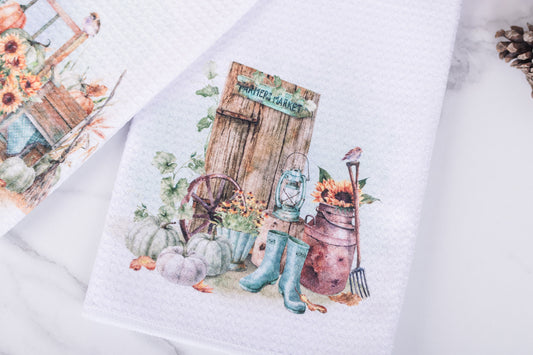 White tea towel with watercolor farmer’s market sign, rustic milk can, lantern, and pumpkins