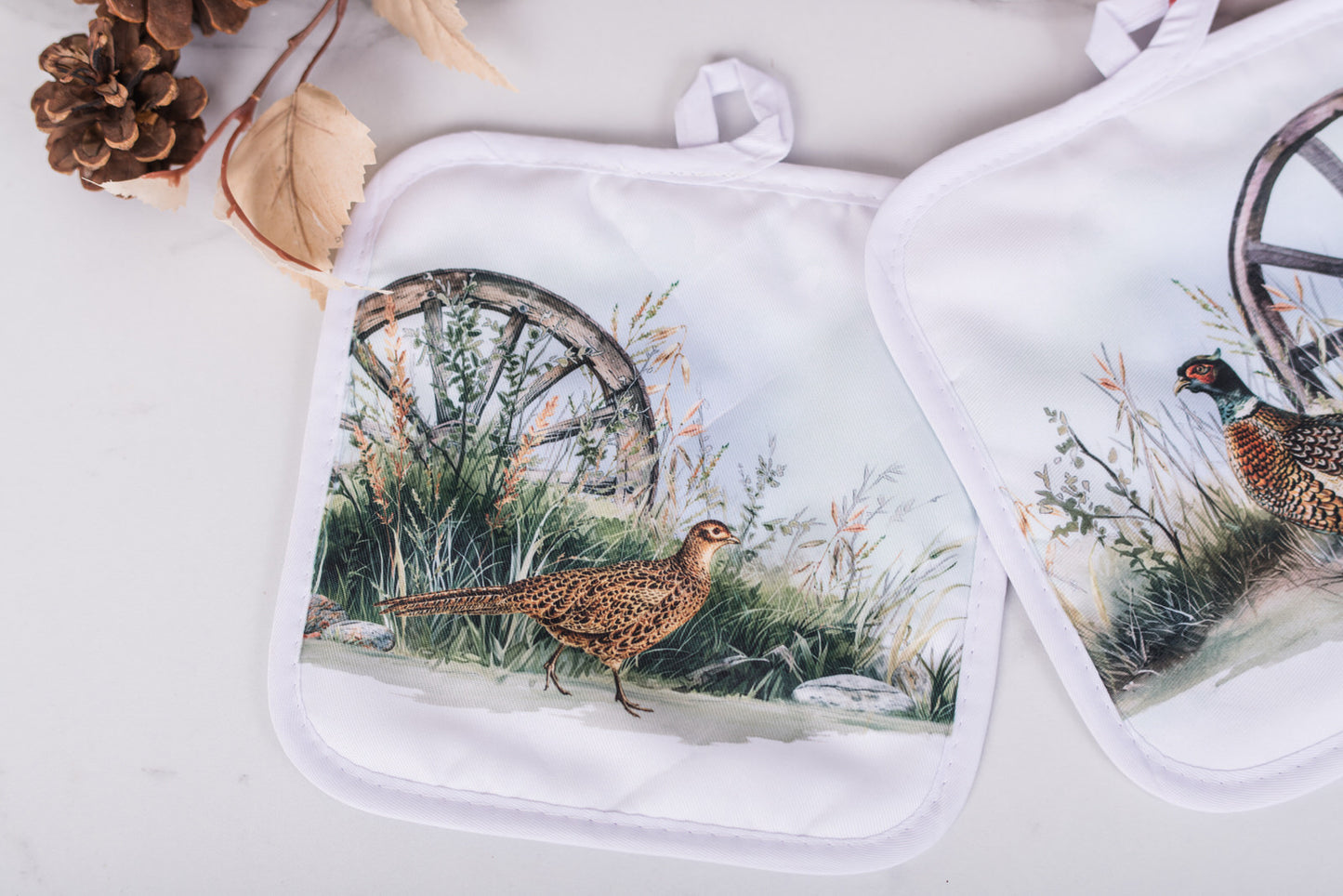 Two pot holders with bird designs on a white surface
