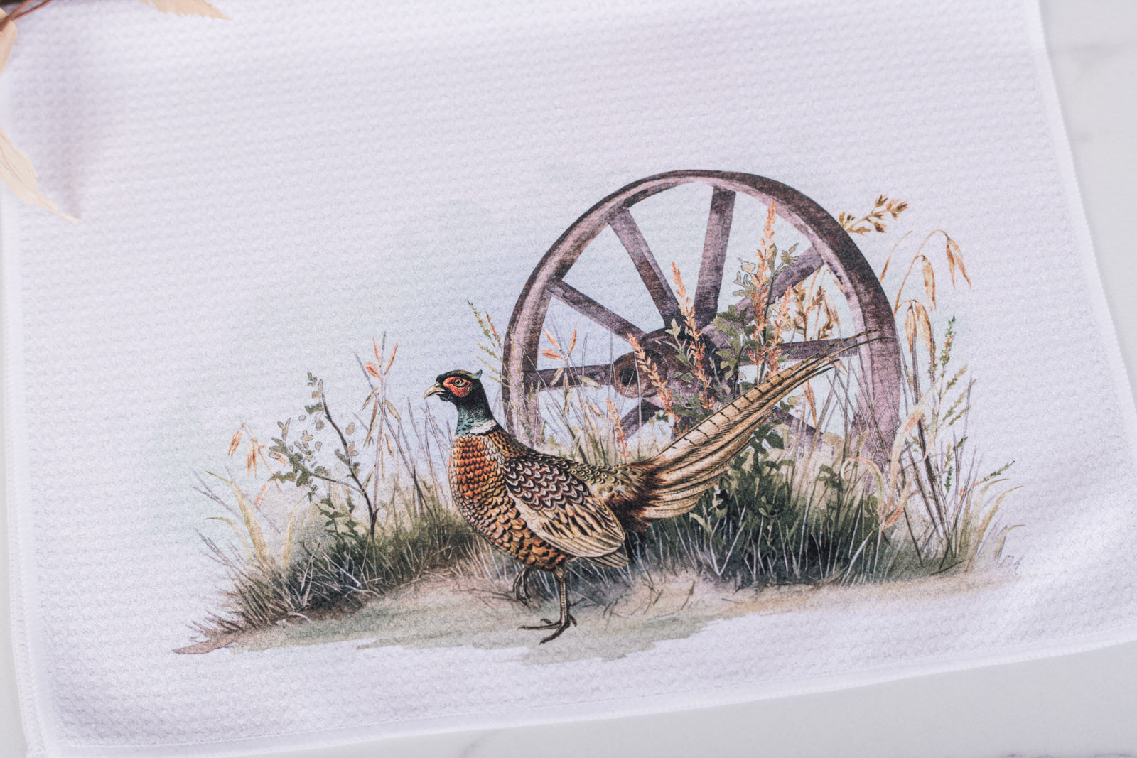 Towel with a pheasant and wagon wheel design on a white background