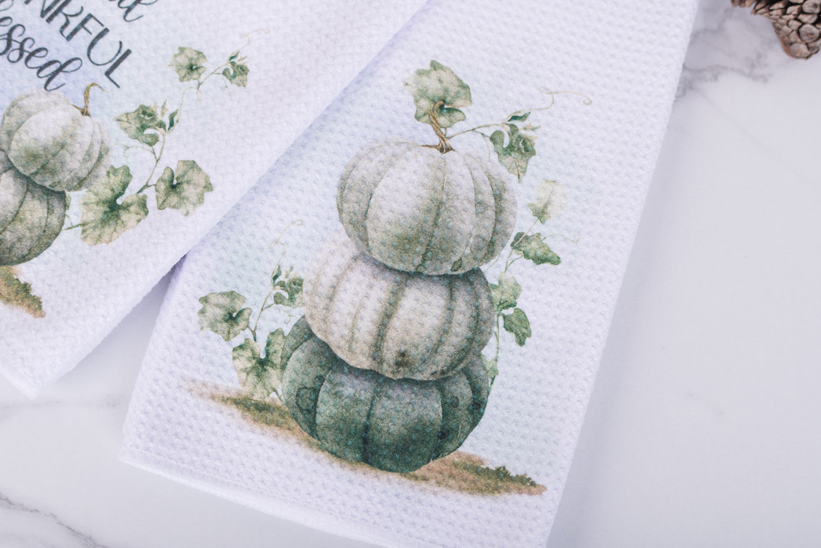 White tea towel with three muted pumpkins stacked with vines in watercolour design