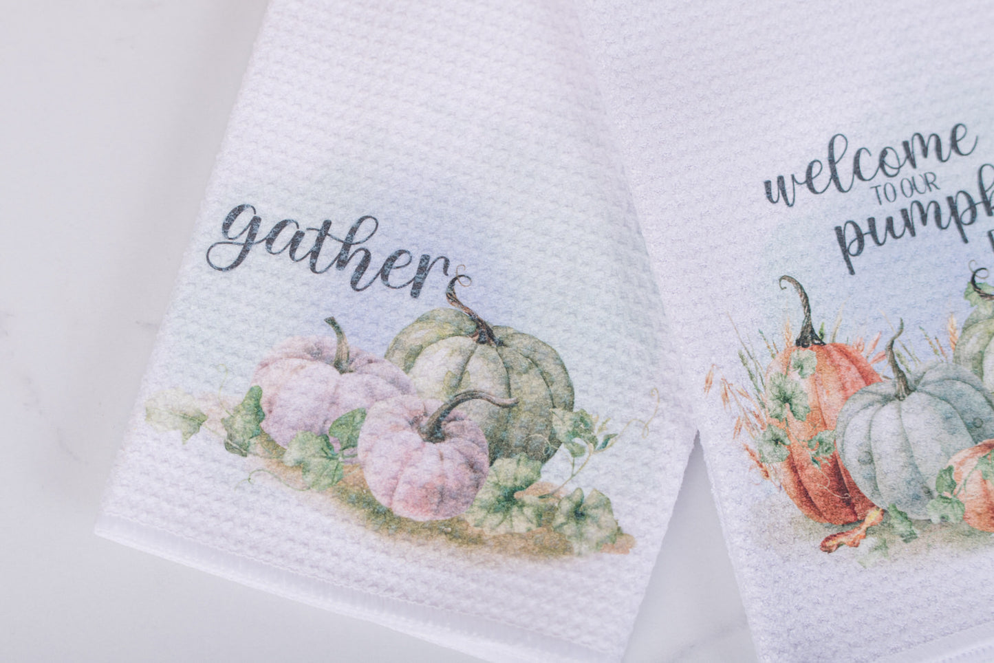 White tea towel with “Gather” text and watercolor pumpkins in green and  white