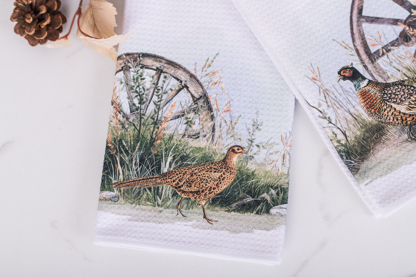 Towels with pheasant designs and rustic elements on a white background