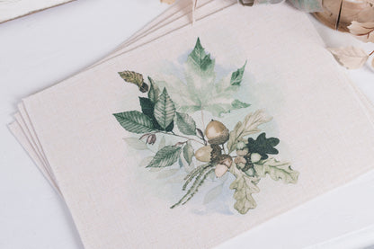 A beige placemat featuring a green floral pattern with various leaves and acorns.
