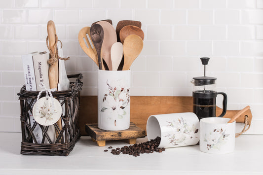 Ceramic magnolia utensil holder on kitchen counter with wooden spoons
