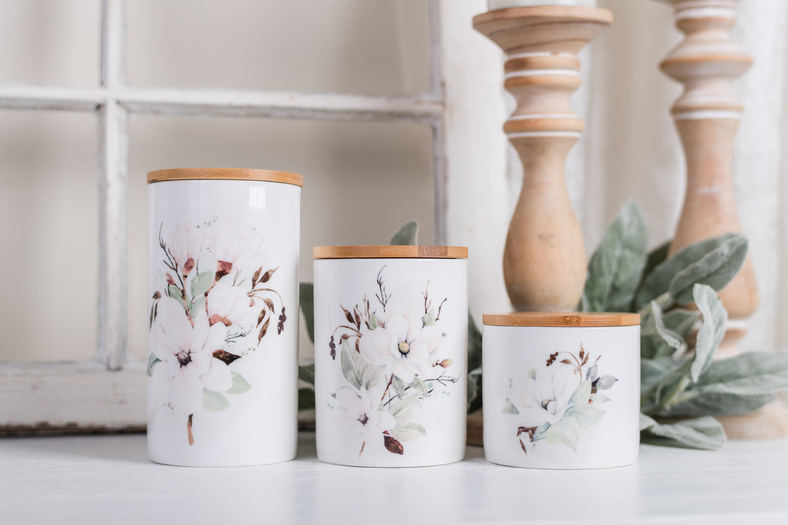 Three decorative canisters with floral patterns on a white surface.