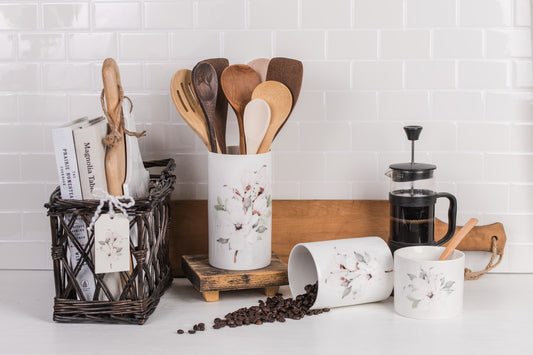 Kitchen utensils and canisters on a countertop with a white tiled wall background