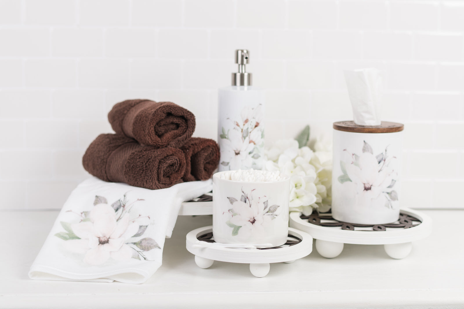 Bathroom set with towels, soap dispenser, ceramic tissue holder and canisters on a white surface