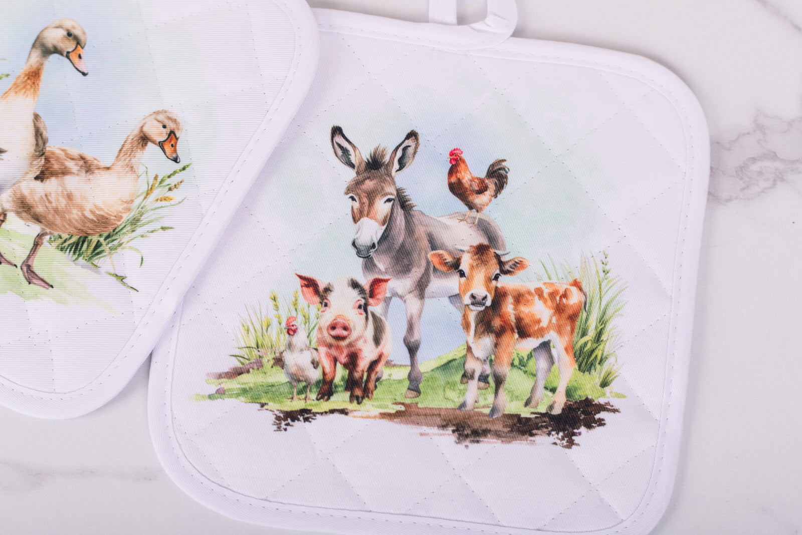 Set of two pot holders with farm animal design on a white background