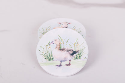 Two round coasters with duck designs on a light gray background