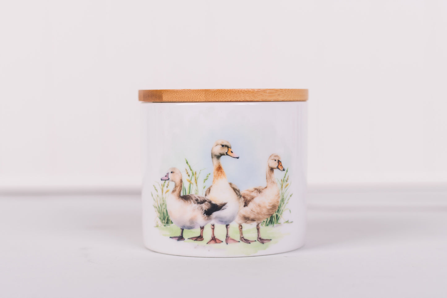 Ceramic jar with wooden lid featuring illustrations of ducks on a white background