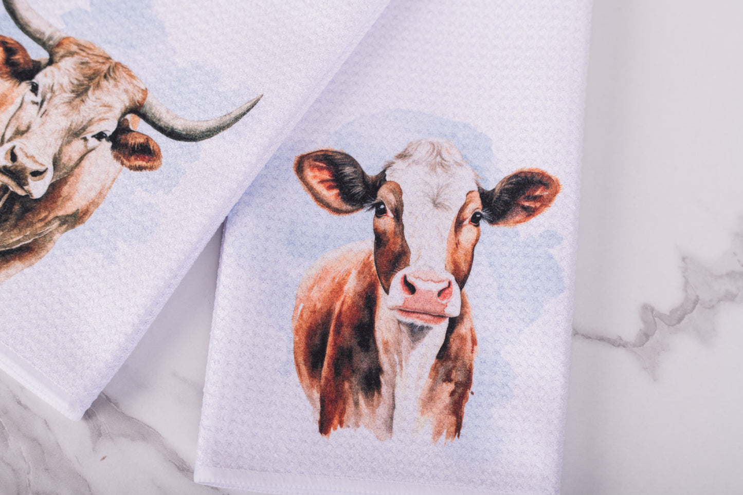 Farmhouse cow tea towel styled on marble surface