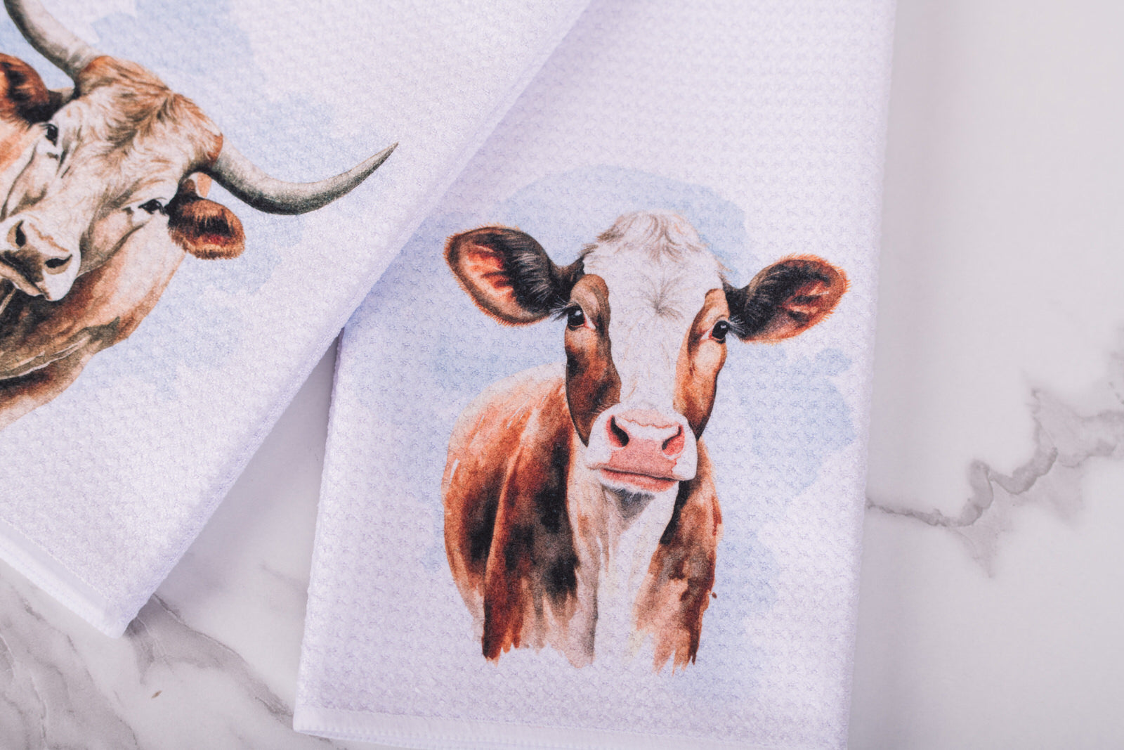Farmhouse cow tea towel styled on marble surface