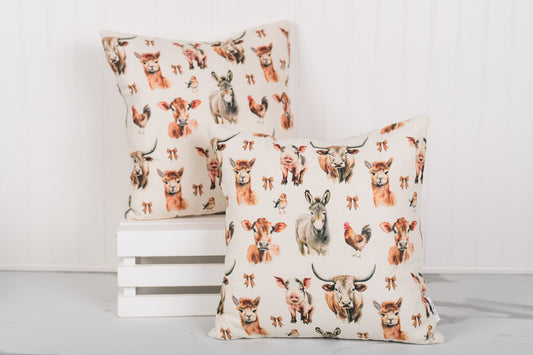 Square farmhouse pillow with cows, pigs, llama, and a rooster on oatmeal fabric