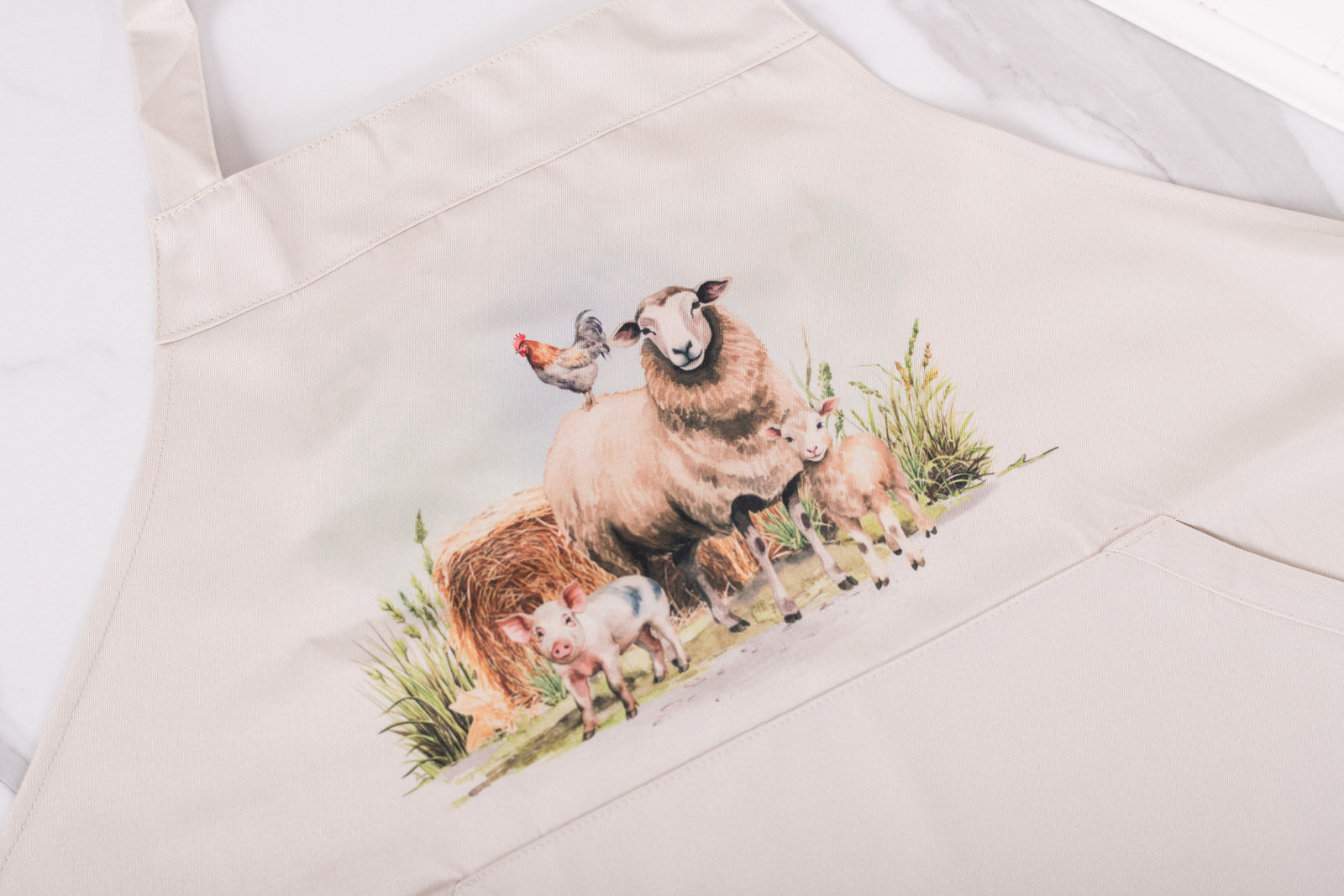 Beige apron with a sheep and lamb design on a white background