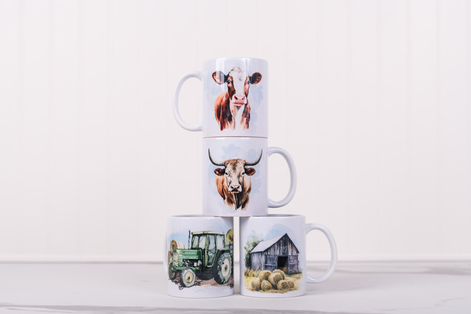 Stack of four mugs with farm-themed designs on a white background