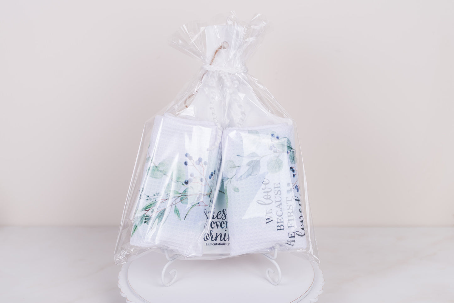 Clear cellophane bag with2 tea towel sand a kitchen trivet on a white background