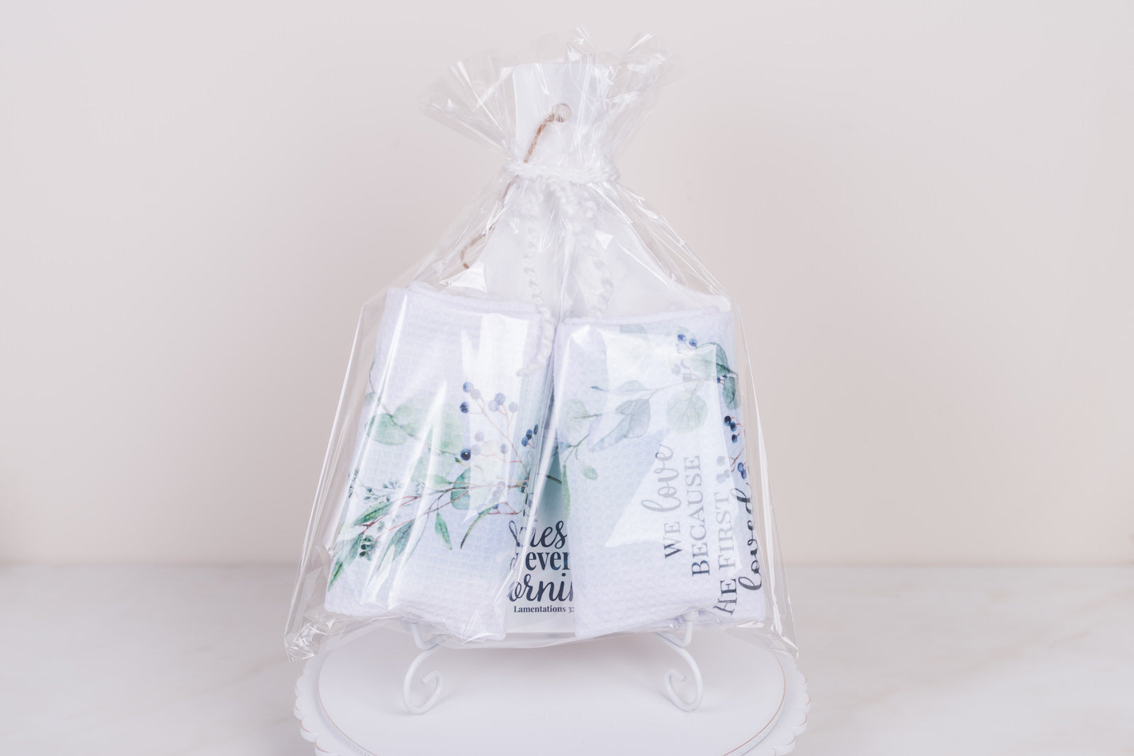 Clear cellophane bag with2 tea towel sand a kitchen trivet on a white background