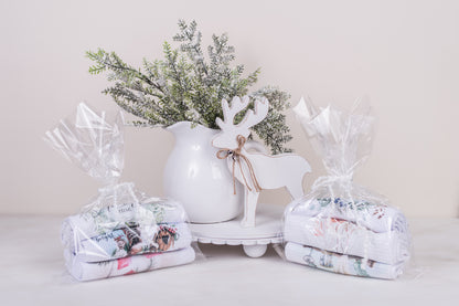 Three curated tea towels bundled with ribbon, holiday-themed
