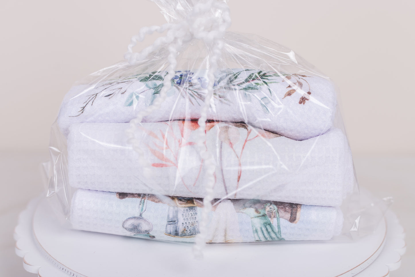 Stack of folded towels with floral patterns wrapped in clear plastic on a white surface