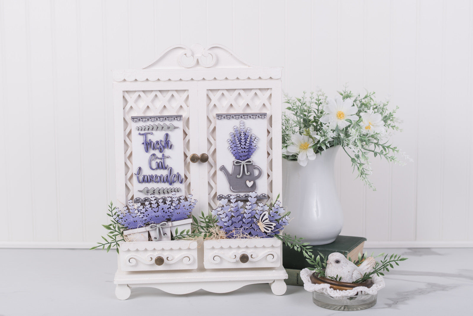 Decorative cabinet with lavender-themed design on a white surface with flowers in the background