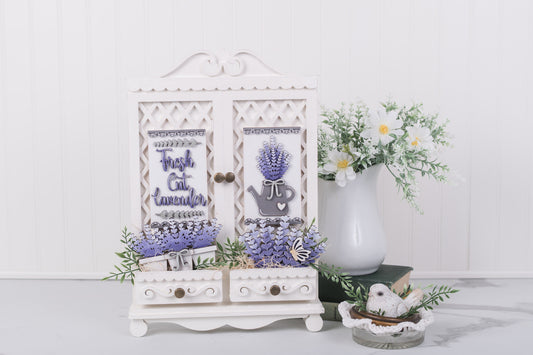 Decorative cabinet with lavender-themed design on a white surface with flowers in the background