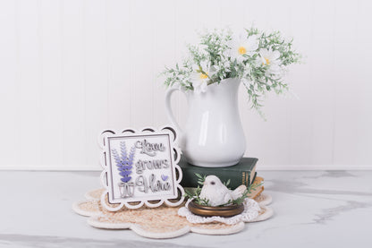 Decorative items including a white pitcher with flowers, a small DIY sign kit, and a bird figurine on a white surface.