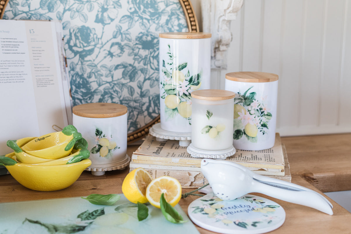 Decorative kitchen canisters with lemon designs on a wooden surface with lemon measuring cups
