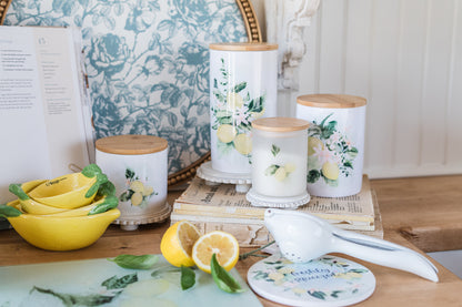 Decorative kitchen canisters with lemon designs on a wooden surface with lemon measuring cups
