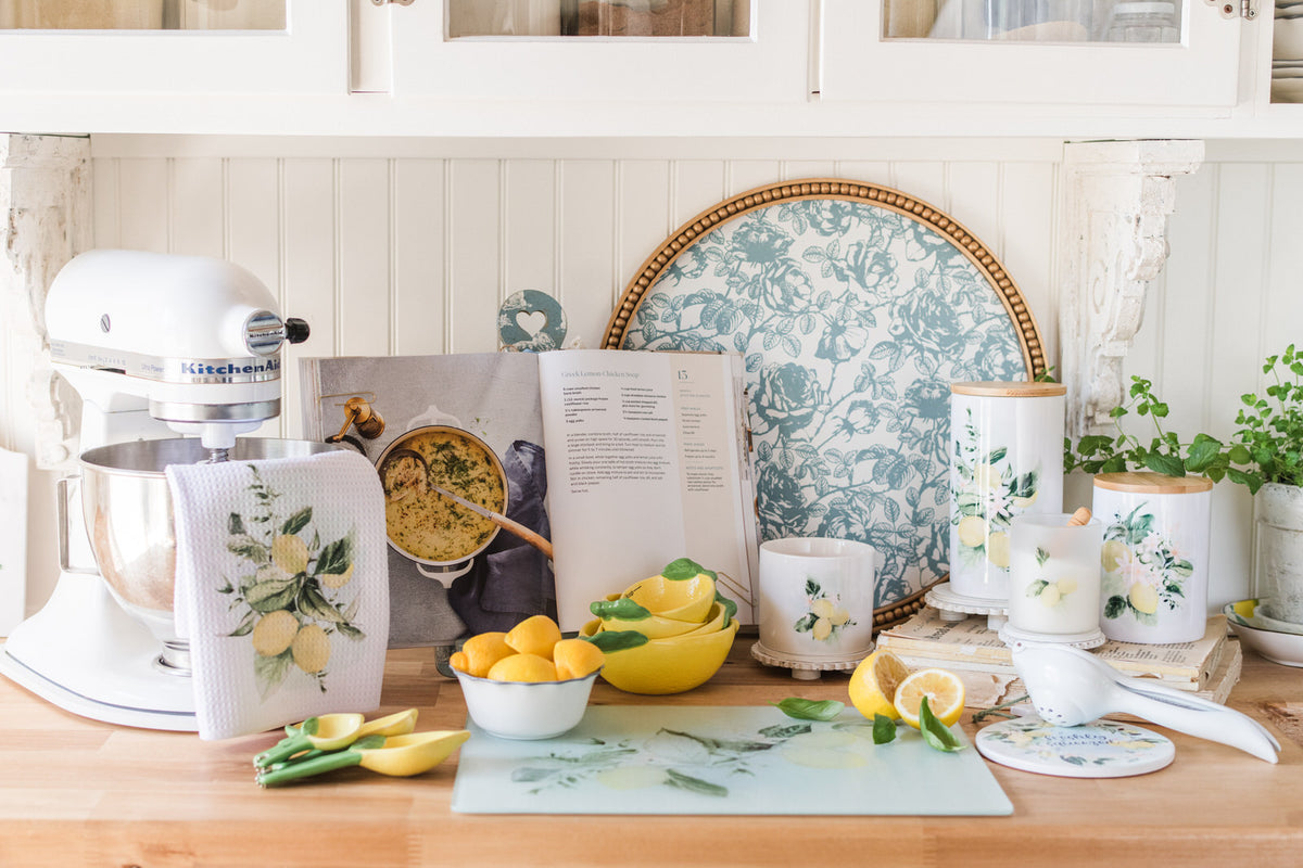Kitchen counter with kitchenware, including a mixer, lemon canisters, cutting board, and more.