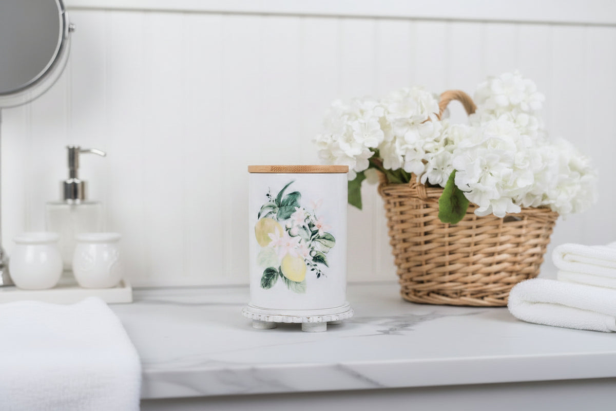 Lemon bathroom canister with a basket of flowers in the background on a marble countertop