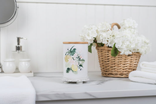 Lemon bathroom canister with a basket of flowers in the background on a marble countertop