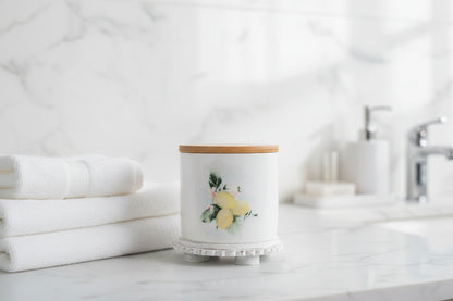 Small lemon canister, styled in bathroom on a white marble surface with white towels in the background
