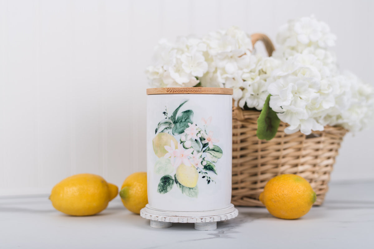 Medium lemon kitchen, ceramic canister, styled with a basket of flowers and lemons on a white countertop