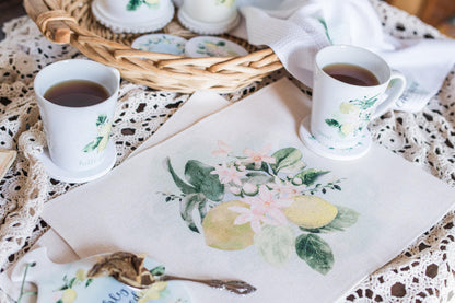 Lemon placemat with soft lemon floral design on table with coordinating tea, cups and coasters